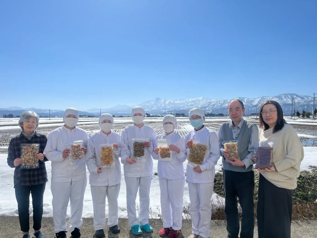雪の田園を背に商品を手にした社員一同